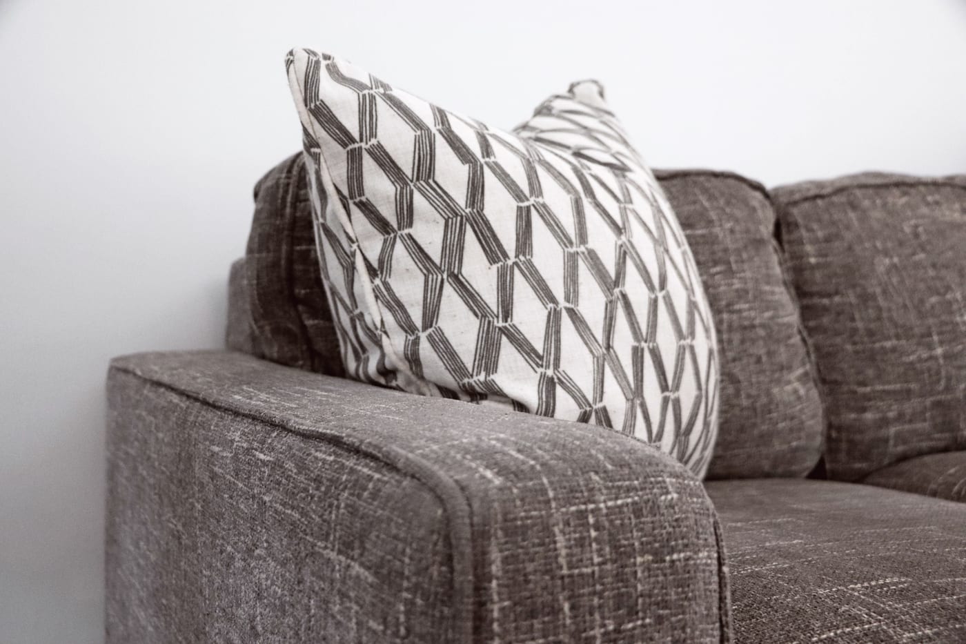 Close-up of a sofa's woven upholstery fabric and a patterned cushion, showing the fibres that trap dust and allergens